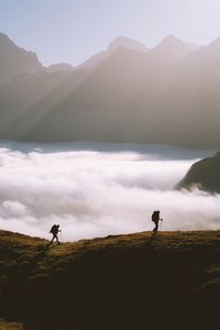 Hikers walking on mountain against sky
