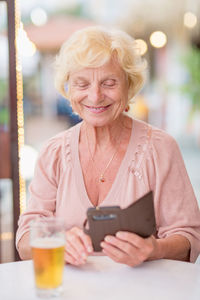 Mature woman sitting at a table in a summer cafe and drinking beer