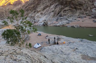 People on rock by water