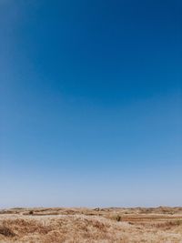 Scenic view of desert against clear blue sky