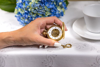 Close-up of woman holding pocket watch on table
