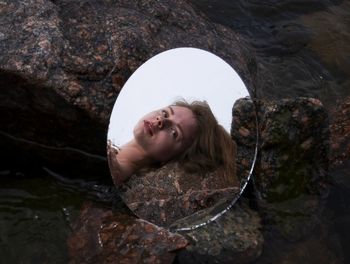 Close-up of woman face reflecting in mirror on rock