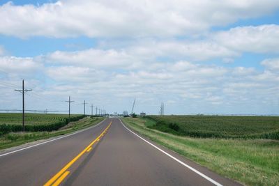 Road amidst field against sky