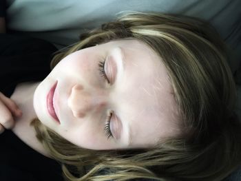 High angle close-up of girl sleeping on bed at home