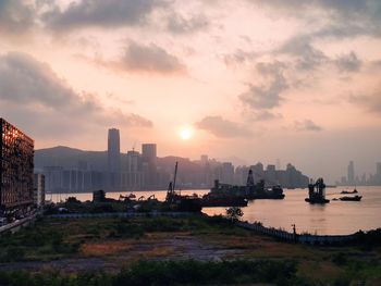 Scenic view of sea and buildings against sky during sunset