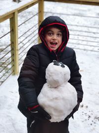 Portrait of smiling boy standing in snow
