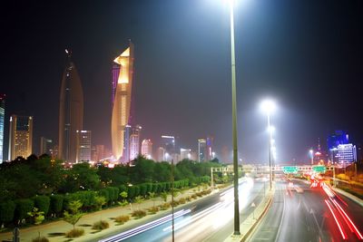 Illuminated street amidst buildings against sky at night