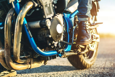 Low section of man riding motorcycle on road