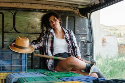 Woman holding hat sitting in van