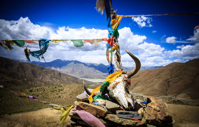 Prayer flags hanging on rope by mountain against sky