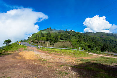Road amidst trees and landscape against blue sky