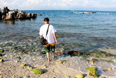 Rear view of man standing on rock at beach