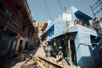 People on street amidst buildings in city against sky