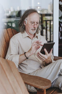 Young woman using phone while sitting on sofa at home