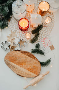  wooden cutting board with wooden rolling pin,  napkin and burning candles, christmas tree sprigs