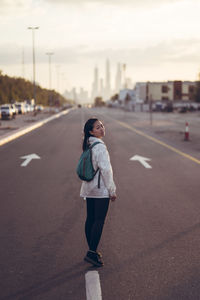 Rear view of woman standing on road in city