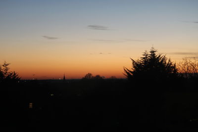 Silhouette trees on landscape against sky at sunset