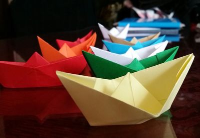 Row of colorful paper boats on table