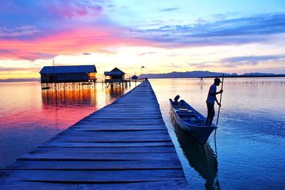 Wooden pier on sea against sky during sunset