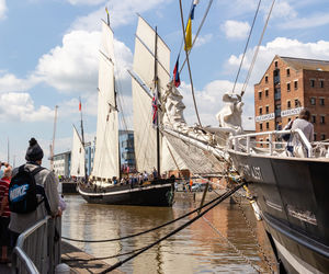 Sailboats moored at harbor against sky