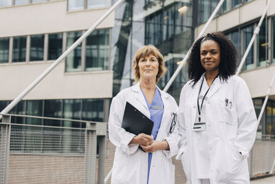 Portrait of confident multiracial female doctors standing in front of hospital