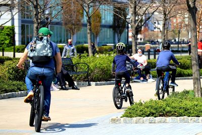 Rear view of people riding bicycle on street in city