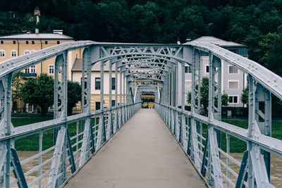 Footbridge amidst trees against sky