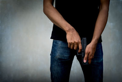 Midsection of man holding woman standing against wall