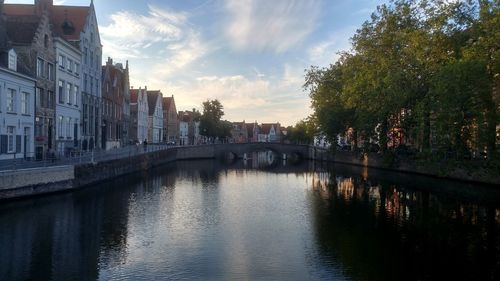 Bridge over river amidst buildings in city against sky