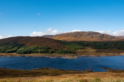 Scenic view of lake and mountains against blue sky