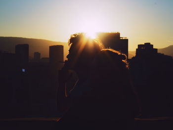 Silhouette woman photographing at sunset