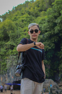 Portrait of young man standing against trees