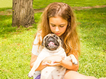 Young woman with dog sitting on grass