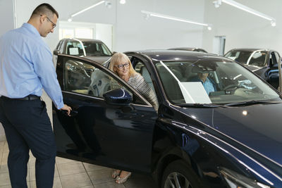 Salesman advising customers in car dealership