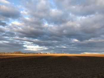 Scenic view of field against cloudy sky