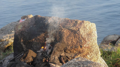 High angle view of bonfire on rock by sea