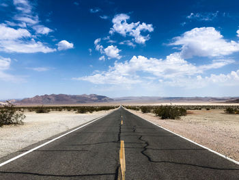 Empty road at desert against sky