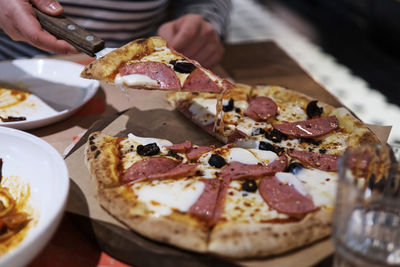 Close-up of hand holding pizza on table