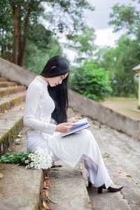 Woman reading book while sitting on steps