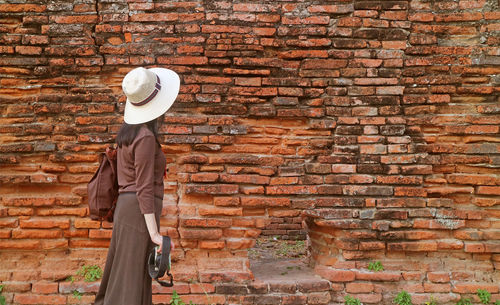 Female traveler walking along the old outer wall of wat phra si sanphet temple, ayutthaya, thailand