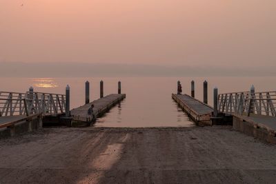 Pier on sea against sky during sunset