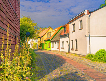 Road amidst houses and buildings against sky