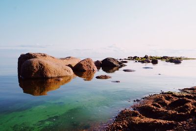 Rocks in sea against clear sky