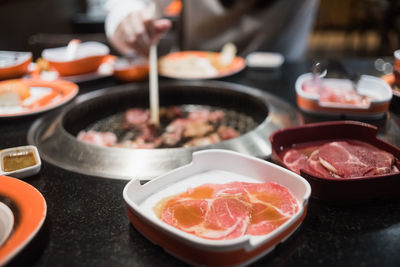 Midsection of woman cooking meat on barbecue grill in restaurant