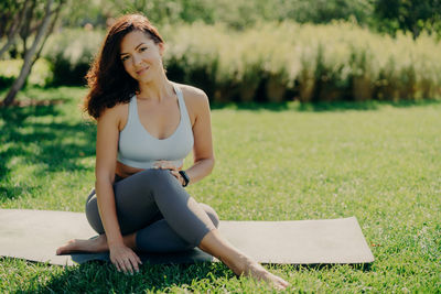 Portrait of woman sitting on mat in park