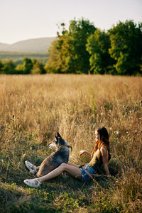 Side view of woman sitting on field