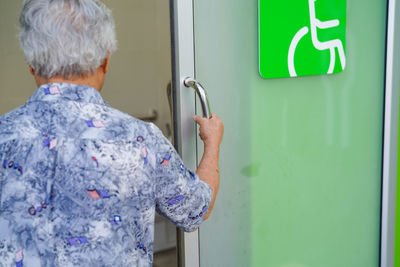 Rear view of woman standing against door