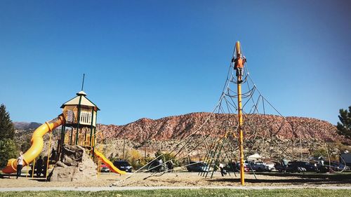 View of playground against clear blue sky