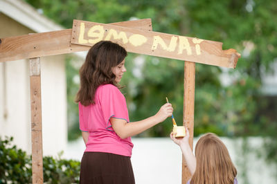 Rear view of woman standing on wood against blurred background