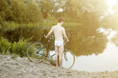 Rear view of woman with bicycle against trees